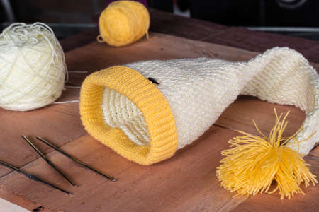 white and yellow crochet knitted winter hat, together with materials to design and knit at home. wool hat designed in an elongated shape. home based entrepreneurship. microenterprise concept.の写真素材