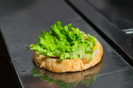 close-up of the beginning of the preparation of a colombian hamburger, in a fast food stand located on the street. bread and lettuce on a metal table. food concept.の写真素材