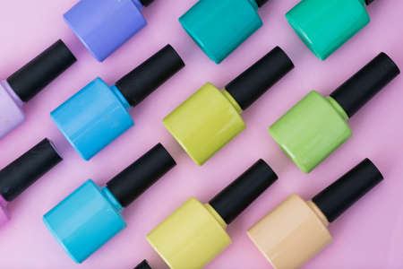Top view of a pattern of nail polishes of different colors placed on a pink, purple, blue, green and yellow background. elements to make a painting and nail design. elements for design. backgroundの写真素材