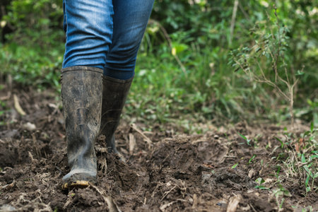 close-up of a latin peasant woman, walking along a muddy road in her marsh boots. girl on her way home through a wasteland. exploring nature.の写真素材