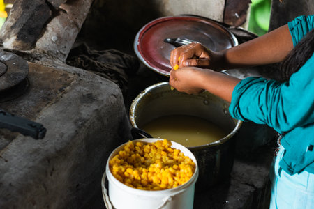 close-up of the hands of a peasant girl pressing hard with her hands the freshly cooked corn to remove the excess water. preparation of yellow arepas. preparation of a colombian breakfast.の写真素材