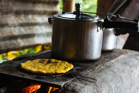 traditional colombian arepa roasting on a typical colombian farm stove. cooking food using wood as...