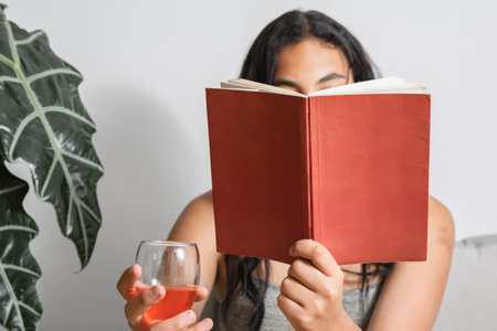 close up of a brunette girl reading a red book that has a clean cover with nothing on it. book template for text and imagesの写真素材