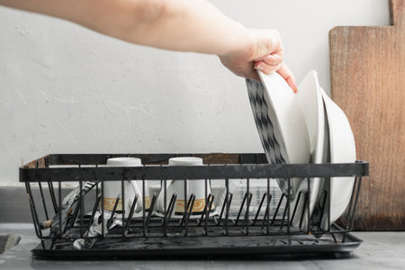 close-up detail of a woman's hand placing the dishes on the drainer to remove excess waterの写真素材
