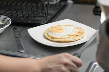 typical colombian breakfast served on a white plate on top of a metal plate. arepa with eggs and small eggs to be eaten.の写真素材