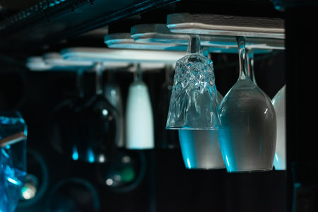 white glasses hanging, placed over a black bar liquor cabinet, with a black background