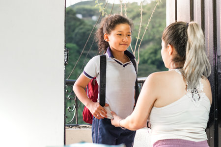 a young mother dismissing her young daughter before leaving for school, looking at her with great prideの写真素材