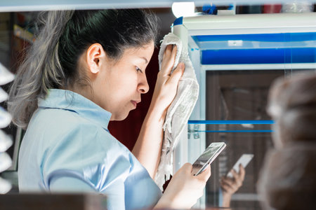 close-up of a young Latina woman, looking at her cell phone while working in a Colombian store.の写真素材