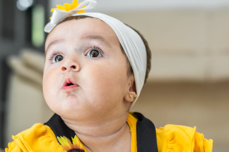 beautiful baby latina, looking up curiously and opening her mouth with a surprised look on her faceの写真素材