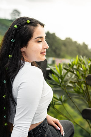 Latina teenager, sitting in an outdoor park, enjoying a moment of freedom.の写真素材