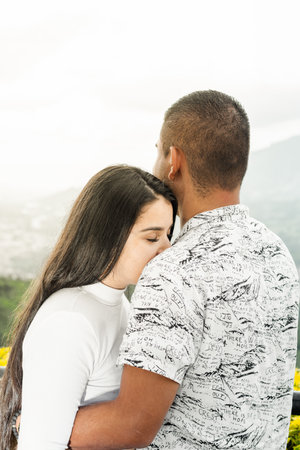 young woman leaning her face on her boyfriend's shoulder, while he looks at the landscape.の写真素材