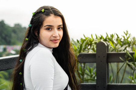 portrait of teenage latina, sitting in an outdoor park, enjoying a moment of freedomの写真素材