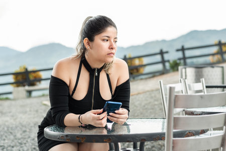 young latin woman, a bit angry waiting for her order, sitting in an outdoor restaurantの写真素材