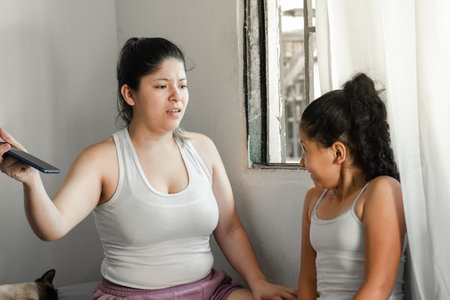 young mother takes away her daughter's cell phone, while the little girl is very angry and looks at her ugly.の写真素材