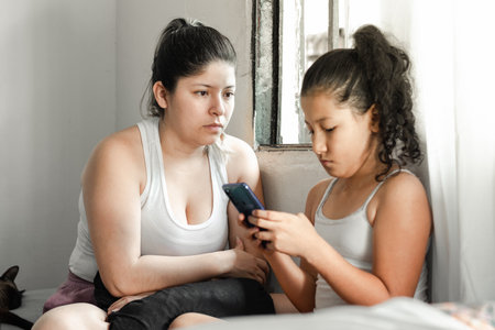 mother looking at her daughter with disappointment because she won't let go of her cell phone. concept of disobedienceの写真素材
