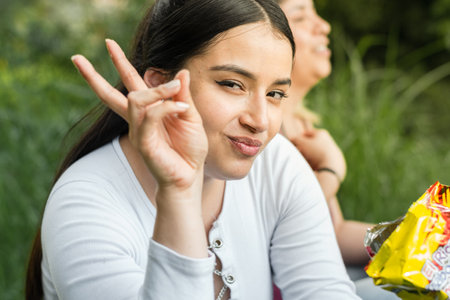 close-up of beautiful young latina woman, making a gesture of peace with her fingers while looking towards the camera.の写真素材