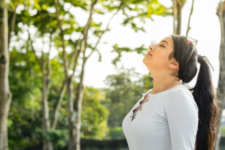 beautiful latina woman, outdoors raising her head to breathe the fresh air of natureの写真素材