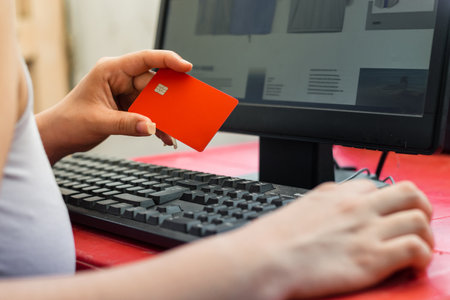 close-up of a hand clutching a credit card, looking at the website to purchase