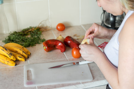 young latina woman peeling an onion to prepare a vegetable saladの写真素材