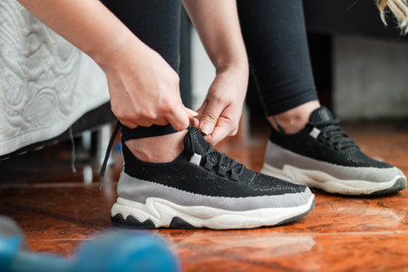 detailed view of the feet of a young woman tying the laces of her sneakersの写真素材