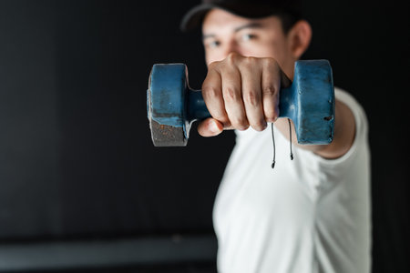 close-up of a Latino man's hand holding a blue dumbbell, working on muscular endurance.の写真素材
