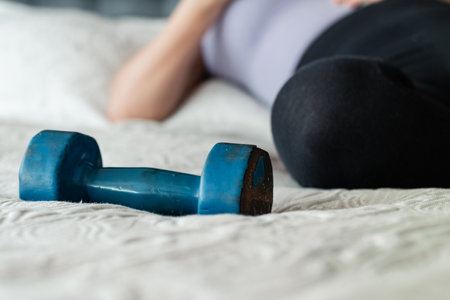 blue, worn dumbbell, placed on top of the bed with a girl lying next to it.の写真素材