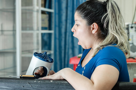 young latina woman very astonished and impressed looking at damaged eletrodomesticoの写真素材
