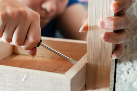 detailed view of a woman's hands, grasping a screwdriver to disassemble a wooden rackの写真素材