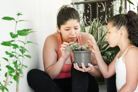 young woman with her daughter watching and checking how her small plant is growingの写真素材