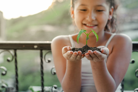 close-up of a very happy brunette latina girl holding in her hand the small plant she planted.の写真素材