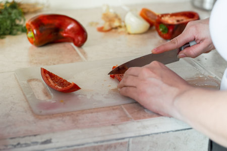 close-up of a girl's hands cutting the red bell pepper for the stew of the mealの写真素材