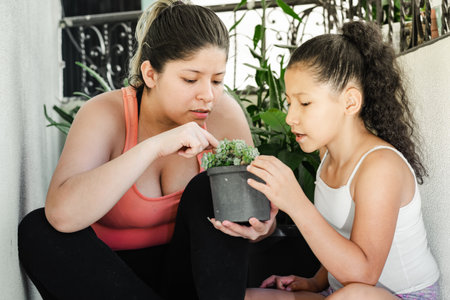 young latina mother with her young daughter checking the growth of the garden silverの写真素材