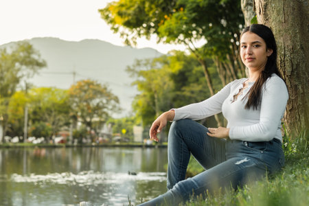beautiful college student sitting to the side with a golden sunset in the backgroundの写真素材
