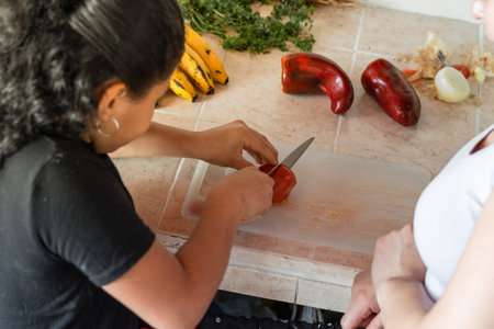 top view of a little brunette girl splitting a tomato, while her mother looks on.の写真素材