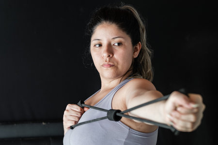 close-up of a young latina woman stretching an elastic band with her hands to exercise her muscles.の写真素材