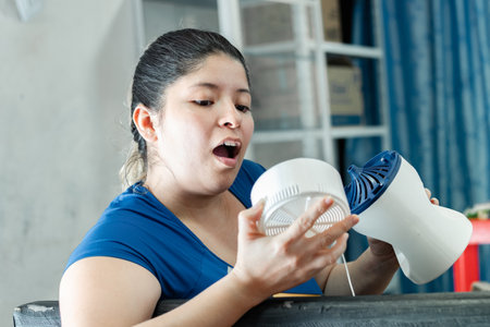 young latina woman looking with great amazement at what the fan looks like on the insideの写真素材