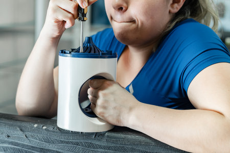 close-up of a young latina woman straining to disassemble a small automatic fly catcherの写真素材