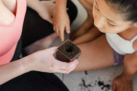 close-up of a brown skinned girl looking attentively at how to plant a plant in the right wayの写真素材
