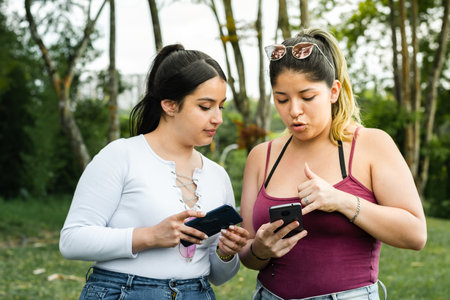 latina girls showing each other the text messages they have on their cell phonesの写真素材