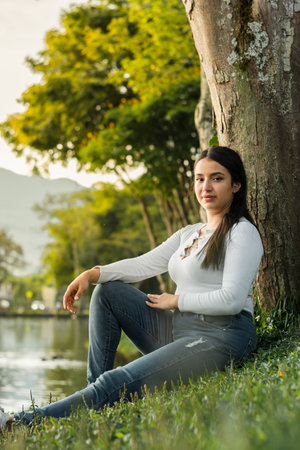 vertical shot of a beautiful female college student sitting to the side with a golden sunset in the backgroundの写真素材