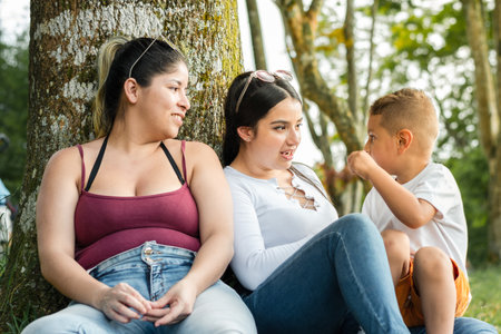 young female couple, listening to their young child talk, while hanging out in the park.の写真素材