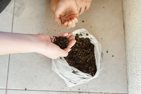 detail of a woman's hand picking up soil from a sack to give to her daughter