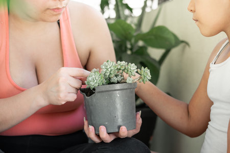 close-up of a little brown-skinned girl asking her mother how to take care of plantsの写真素材