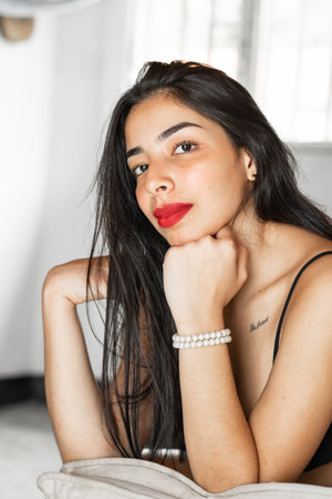 portrait of a brunette latina teenager posing frontally resting on her handsの写真素材