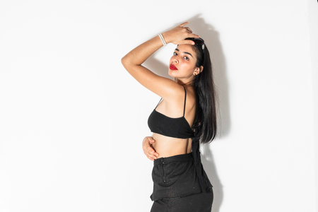 portrait of young brown-skinned latina woman posing sideways with one hand on her headの写真素材