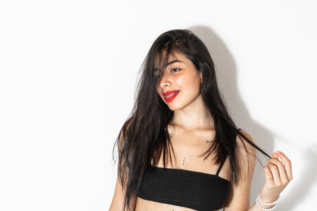 beautiful latina woman posing on a white background with a charismatic smile and a distracted gazeの写真素材
