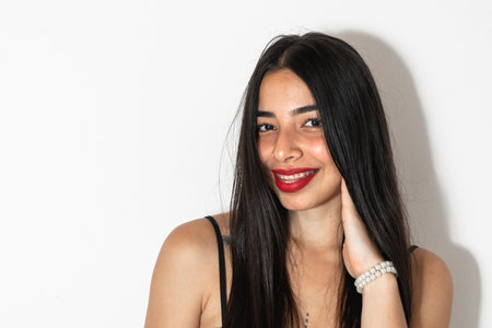 close-up portrait of a beautiful young latina woman with a hand on her cheek smilingの写真素材