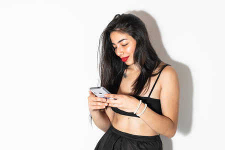 beautiful brunette latina woman, with cell phone in her hands looking very happy, on a white backgroundの写真素材