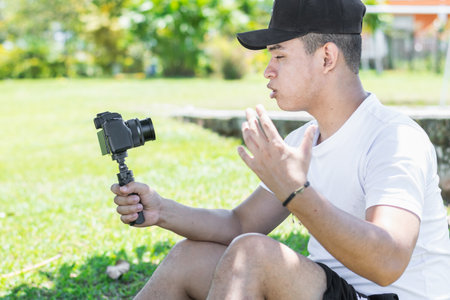 Young Latino man creating a video vlog, explaining the progress of his summer trip, holding the camera with his hand.の写真素材