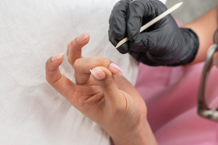 close-up of a woman's hands using a wooden stick to remove manicure blemishesの写真素材